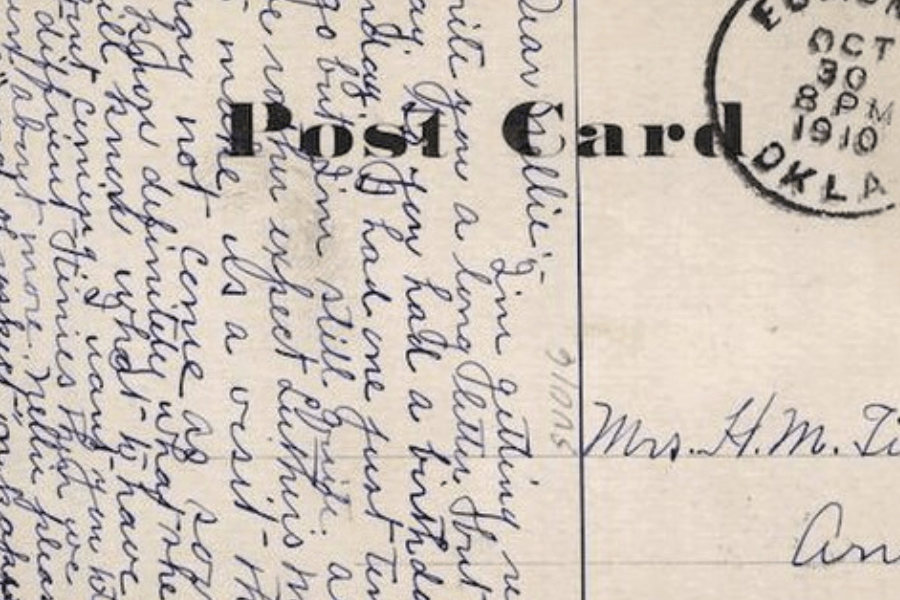 Close-up of a handwritten postcard dated October 30, 1910, from Edmond, Oklahoma. The cursive writing fills nearly the entire left side, with the word "Post Card" partially visible in bold and addressed to "Mrs. H. M. T—" on the right. The blue ink and looping penmanship convey a personal and intimate tone from the early 20th century.