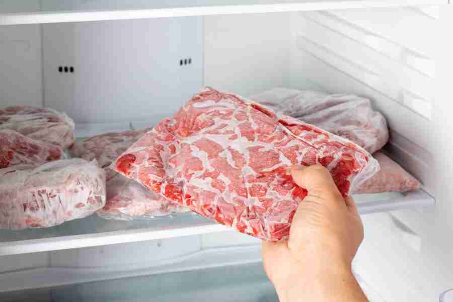 Man taking out frozen meat from freezer. Frozen food