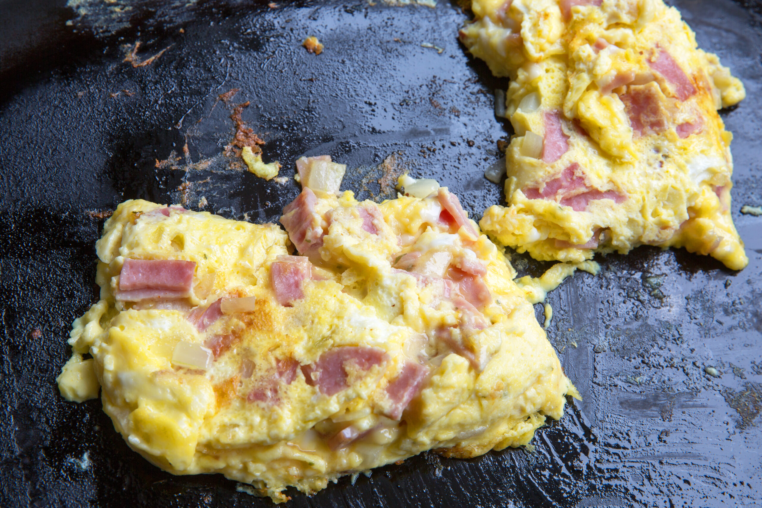 toasted western sandwich egg mixture cooking on greasy fry pan closeup