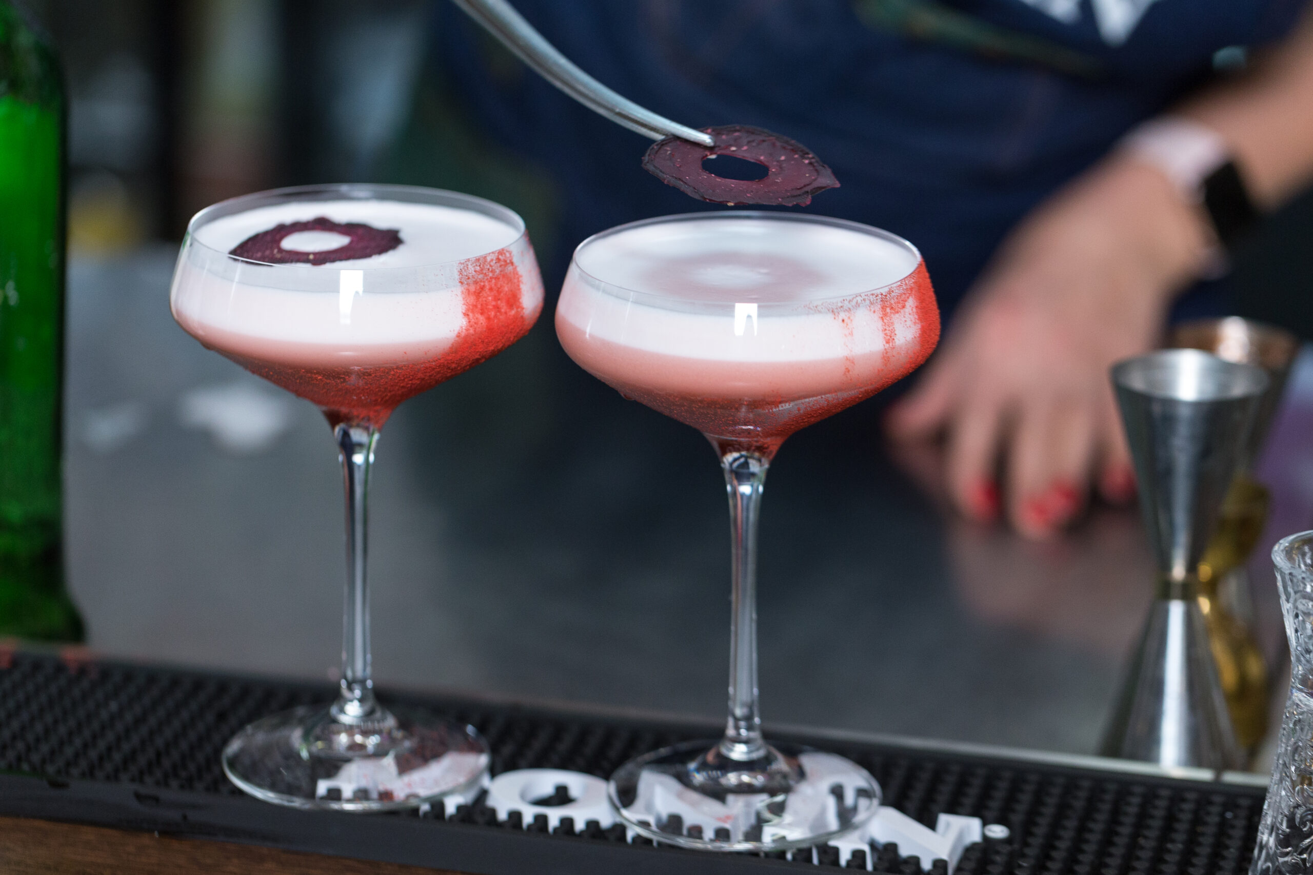 A professional bartender decorates a prepared cocktail.