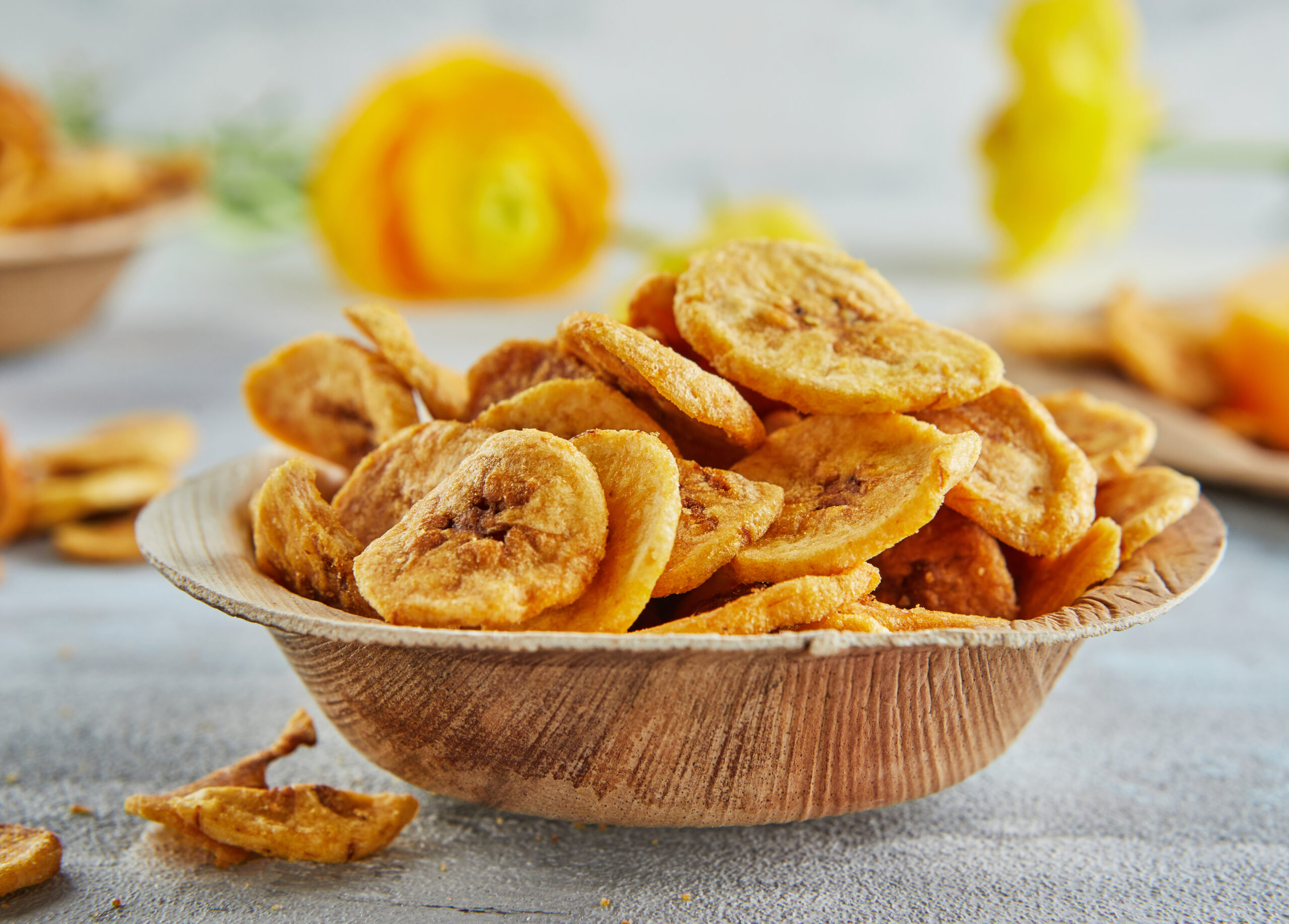 Banana chips healthy food, dry fruits and healthy vegetable chips, healthy vegan snack on background of yellow flowers.