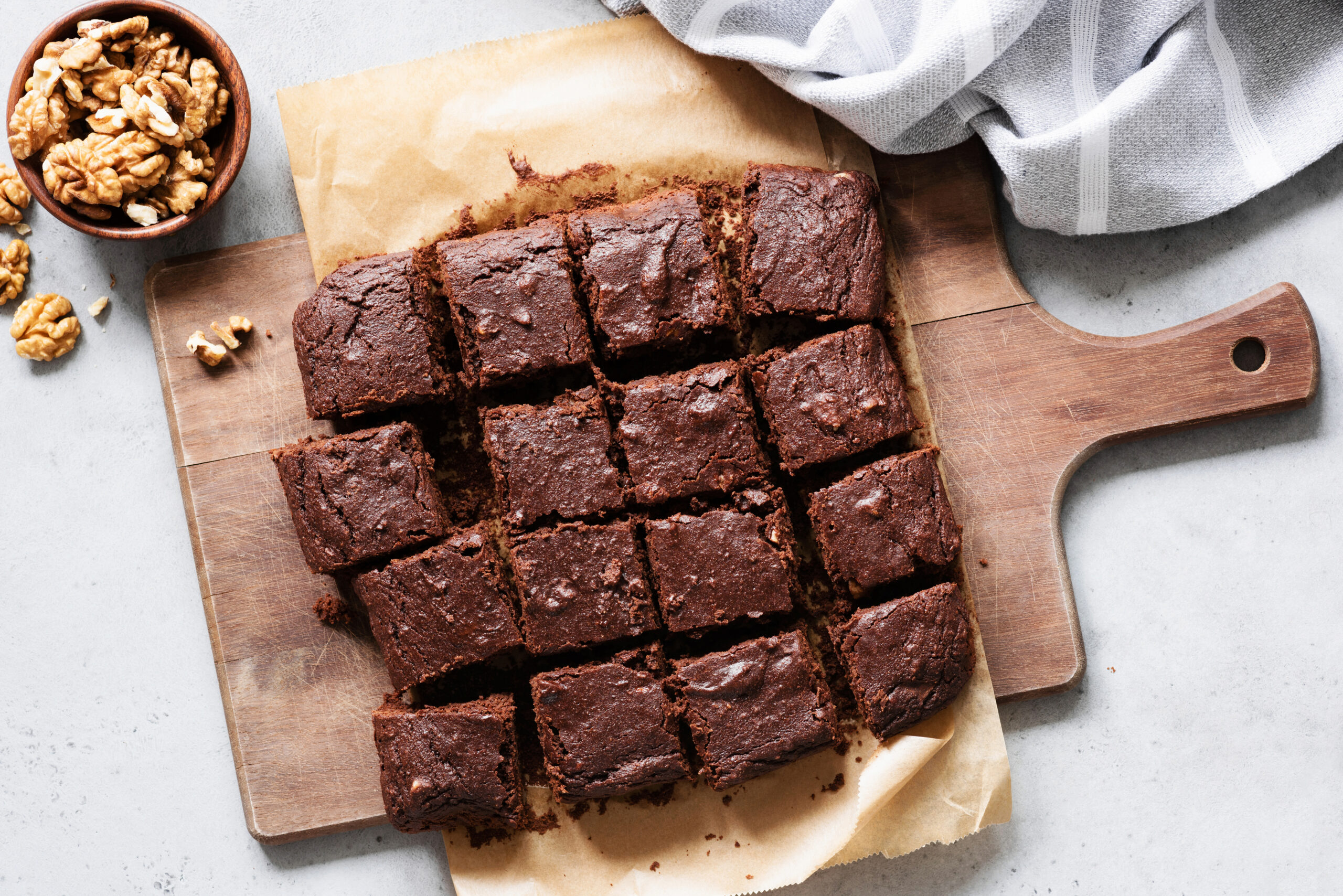 Chocolate brownie squares with walnuts on cutting board, top view, horizontal composition. Flat lay food