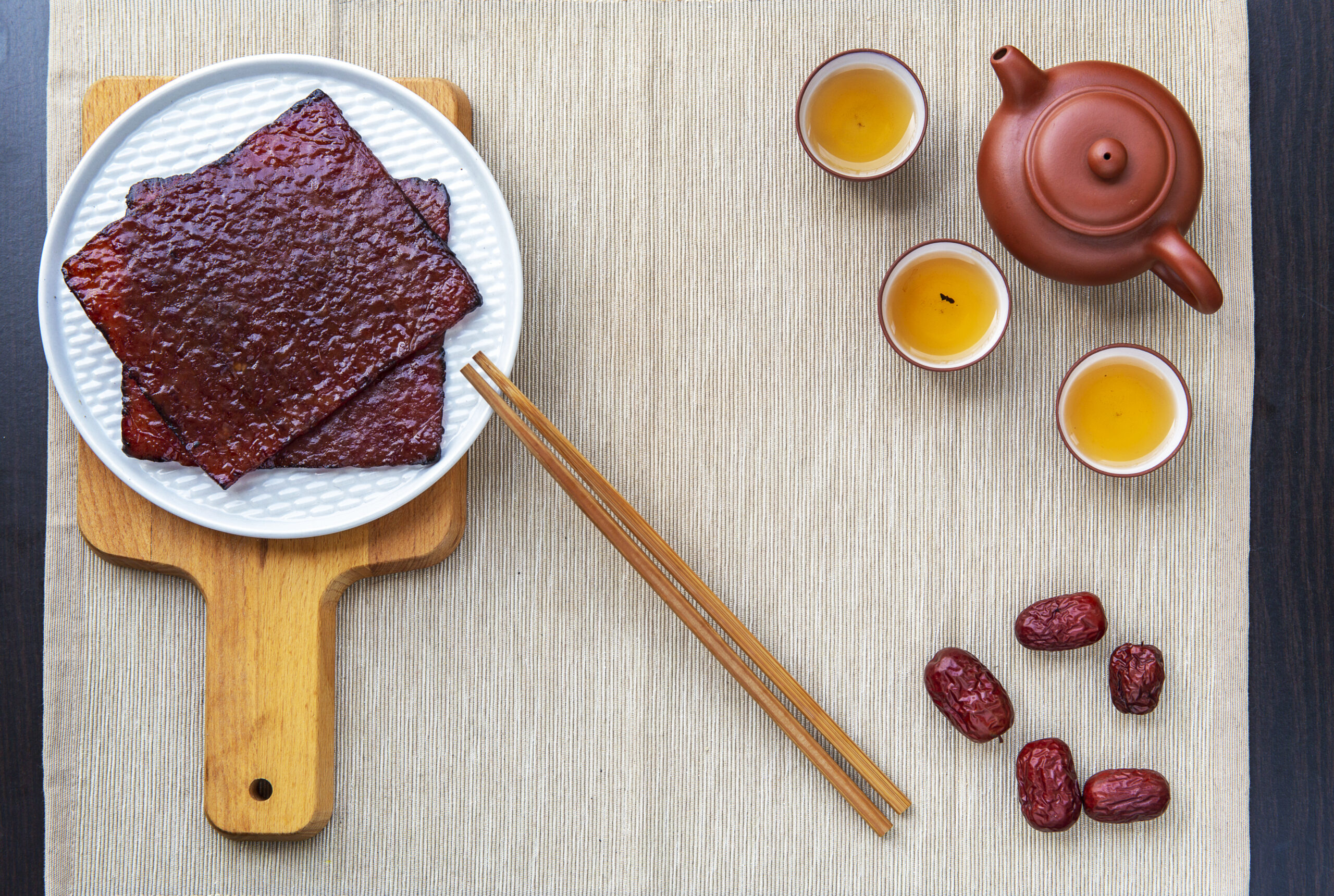 flat lay of Chinese pork jerky (Bak Kwa) slices sered on table with Chinese Tea and dried dates, and copy spaces