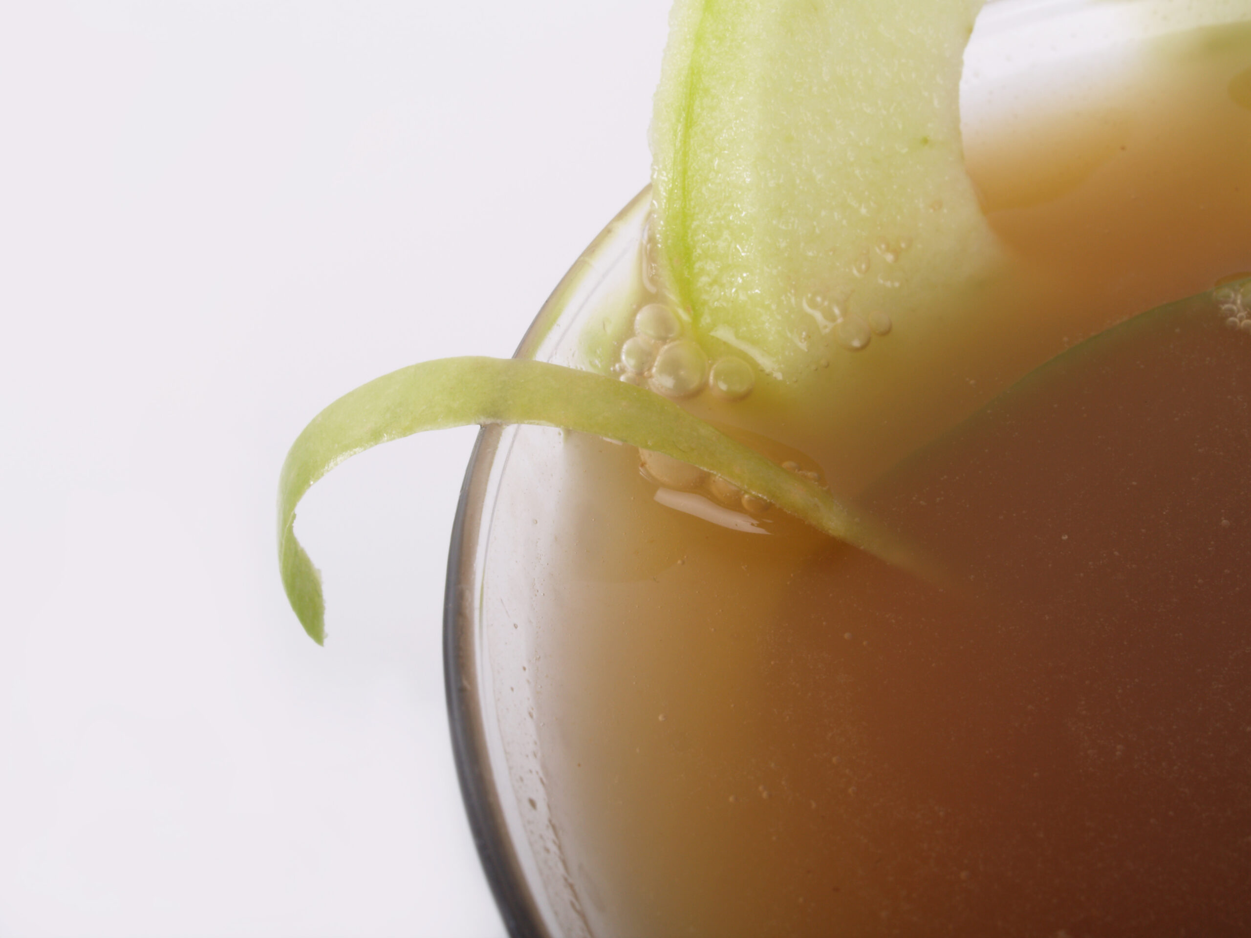 Macro of curled apple zest on a trendy apple martini; could also be apple cider served in the autumn or winter