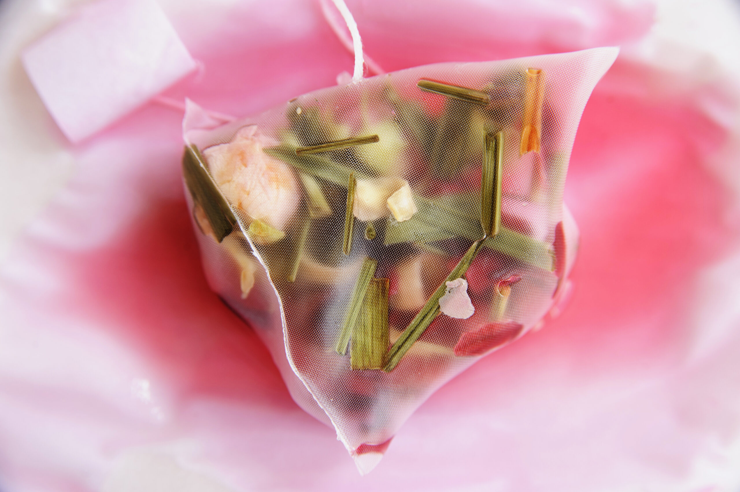 Rose Garden teabag with flower buds, petals and leaves visible through the bag, wet and leaking, with visible teabag string and tag