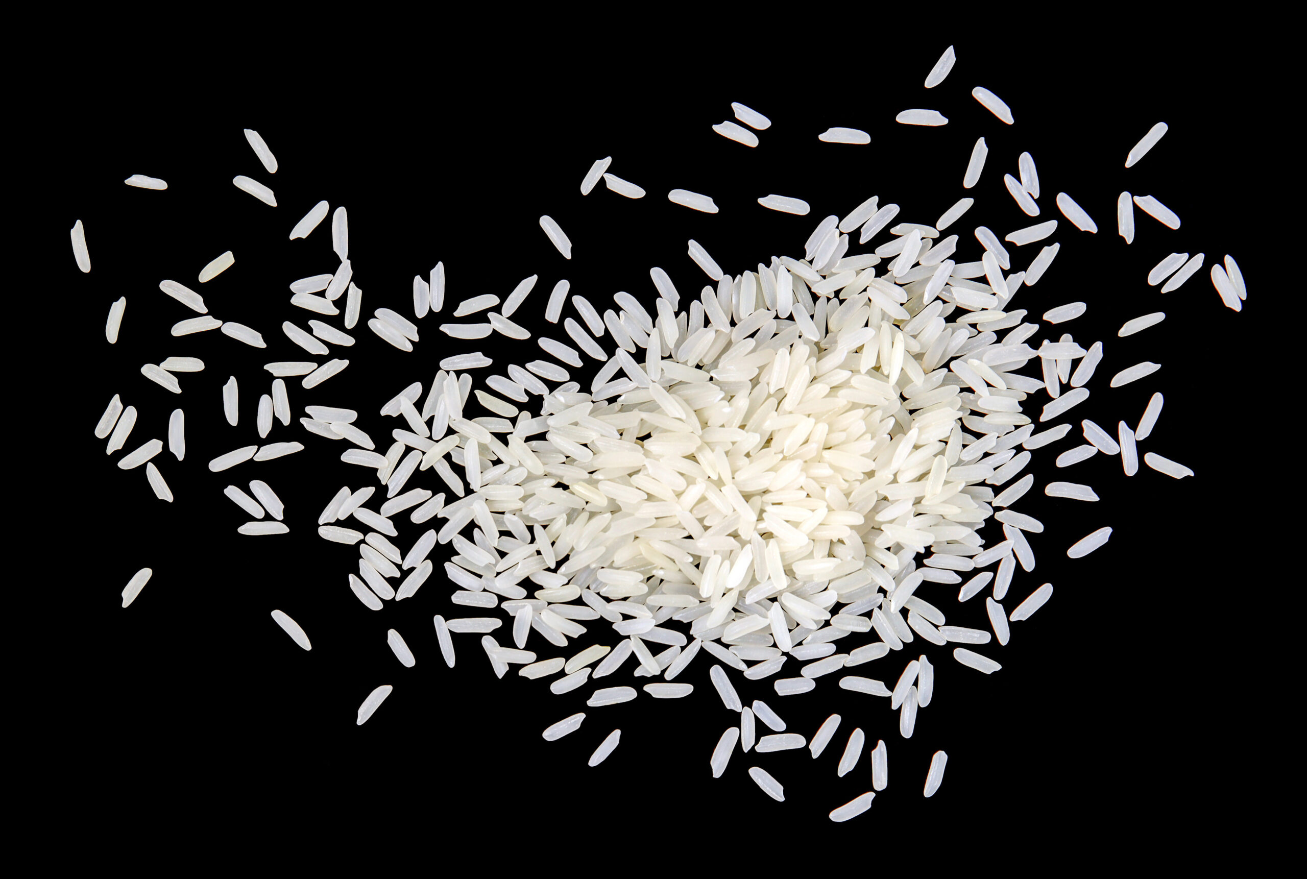 Top view, close-up. A pile of white uncooked rice grains, lying flat. Isolated on black background.