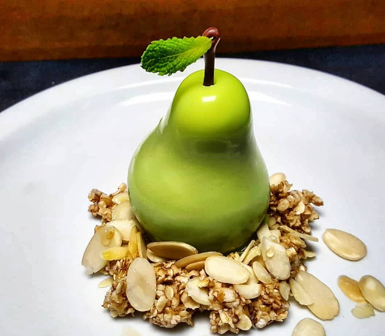 A pear sitting on a bed of almonds, food optical illusion by chefbenchurchill instagram