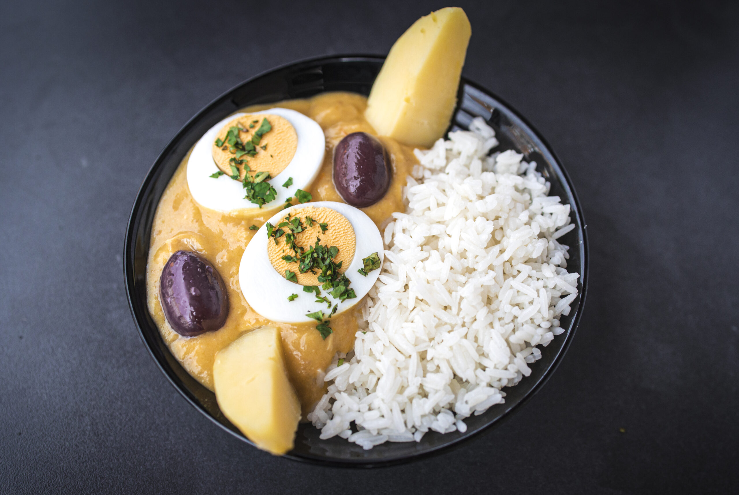 Aji de gallina or Peruvian curry is a comfort chicken stew served with rice at the table. Top horizontal view from above