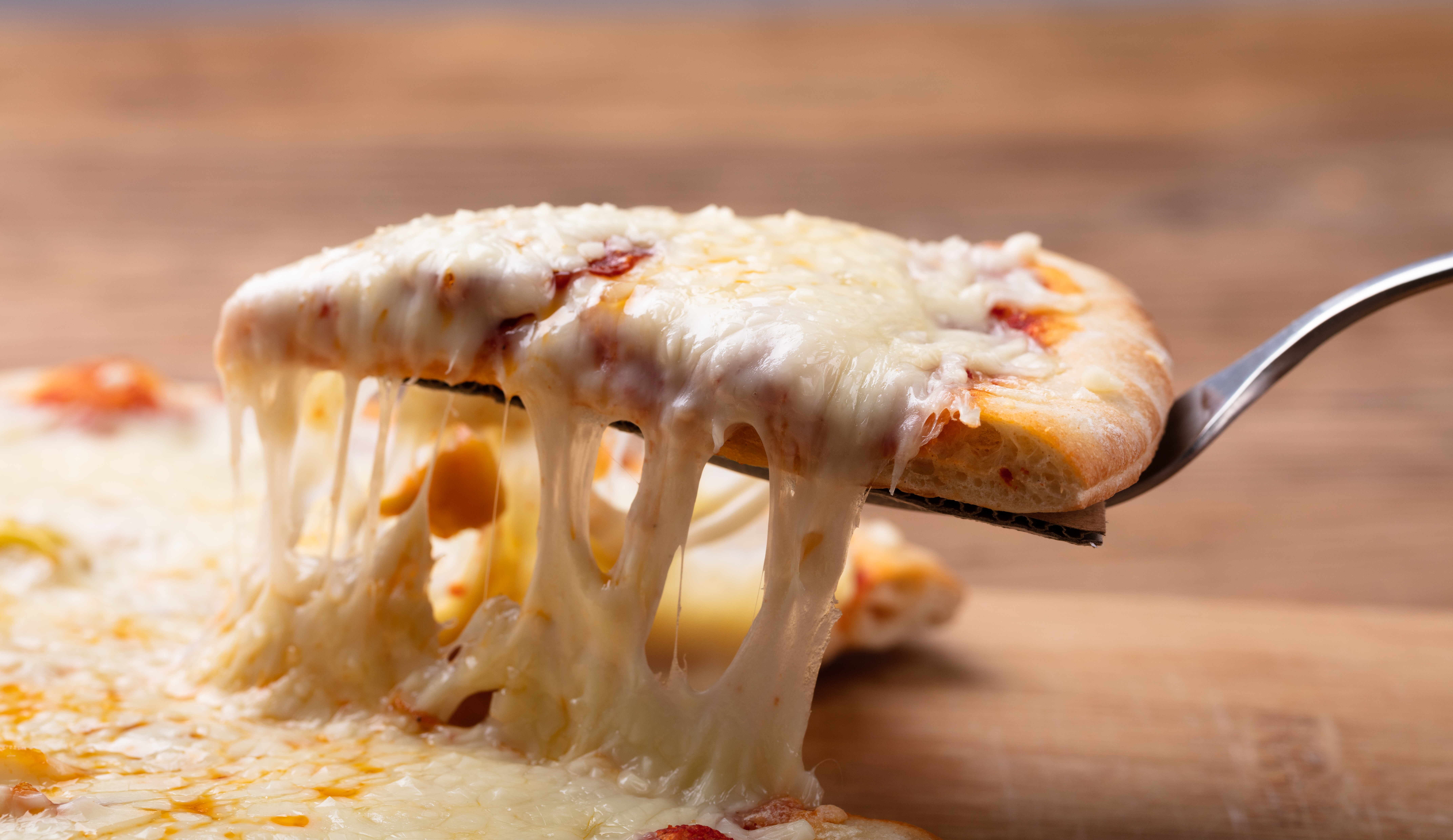 Close-up Of A Delicious Cheesy Pizza On Wooden Table