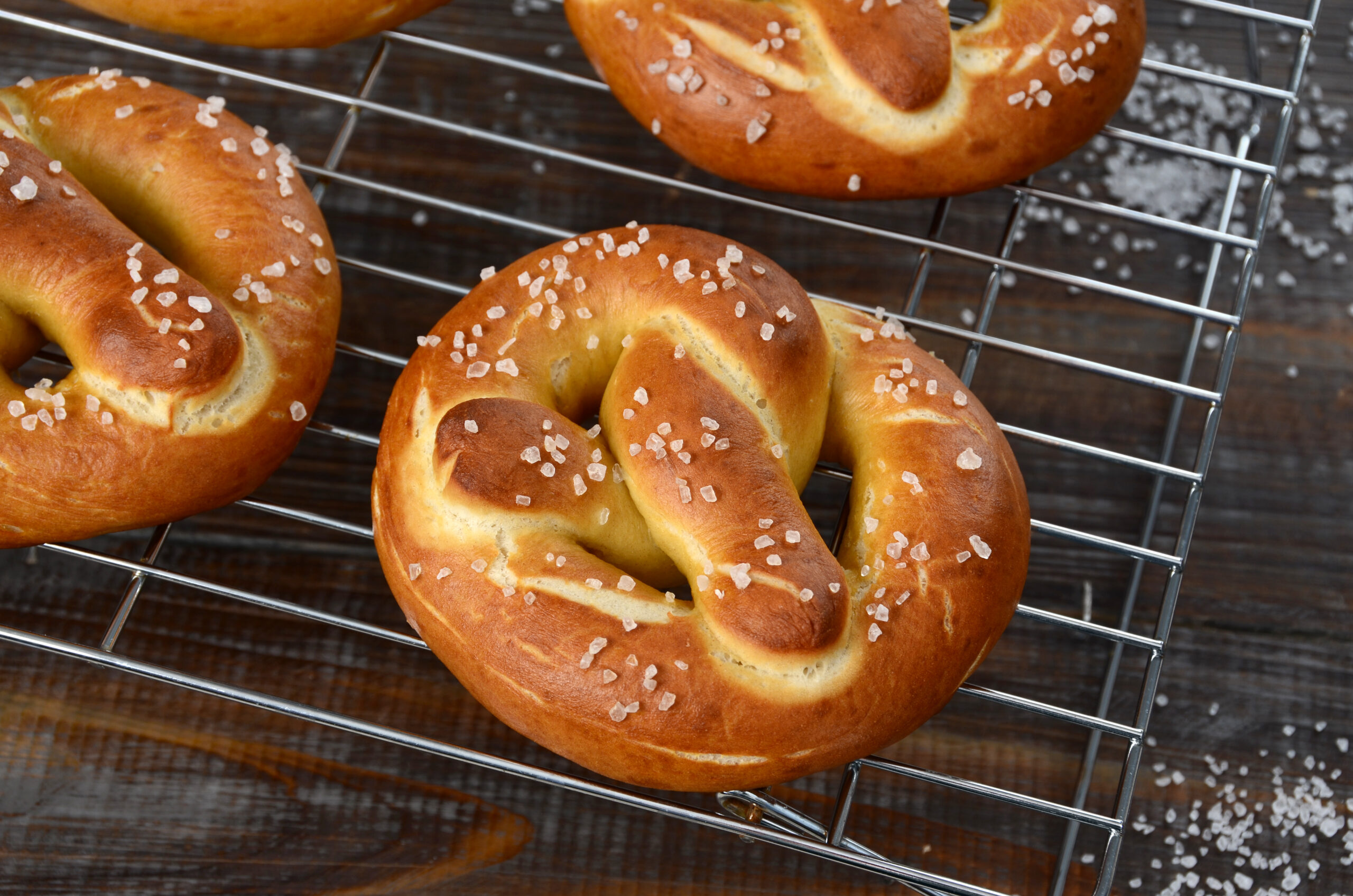 Freshly baked Bavarian style soft pretzels cool on a rack.