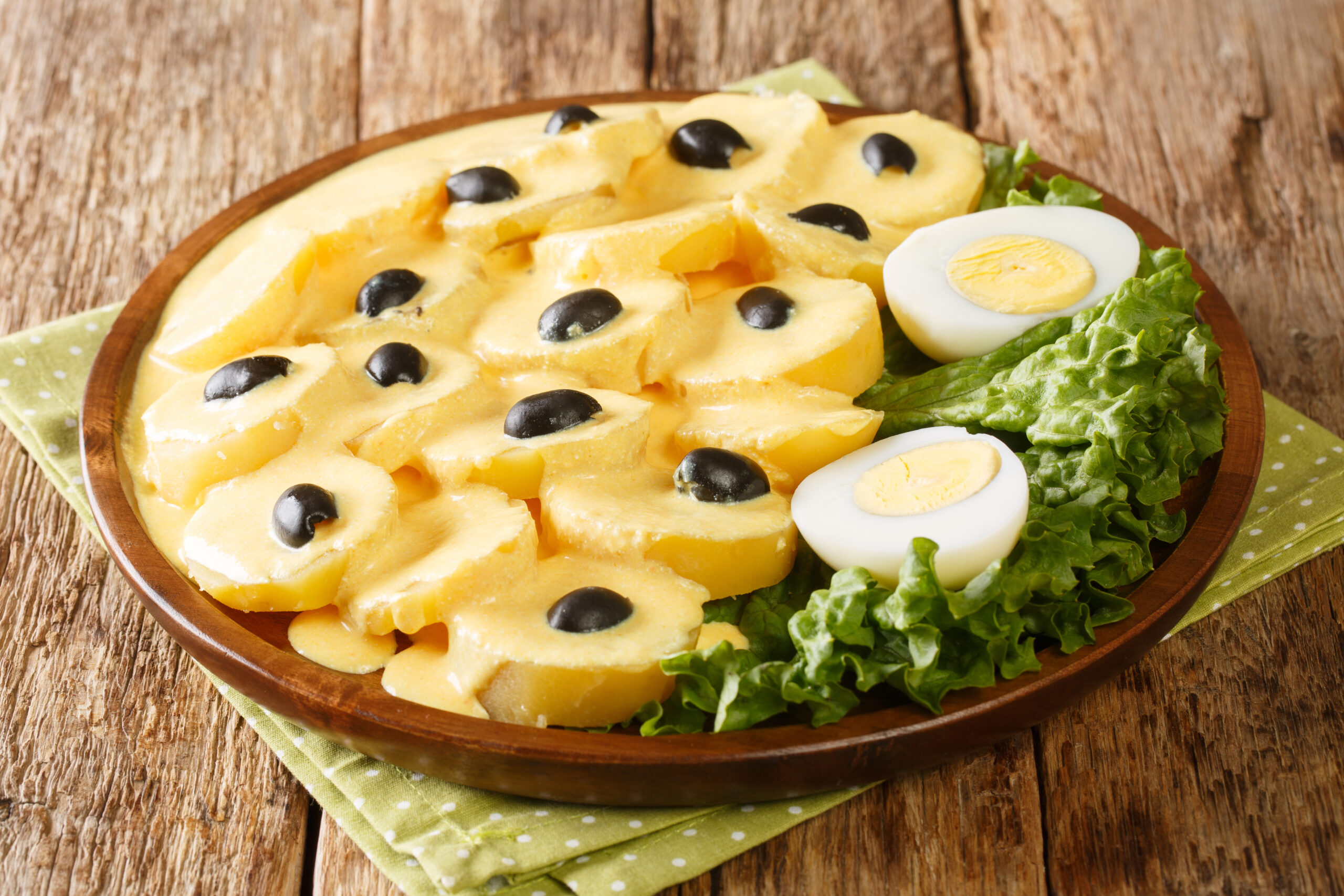 Peruvian cuisine Papa a la huancaína or potatoes Huancayo style boiled potatoes are topped with a creamy cheese sauce close up in the plate on the table. Horizontal
