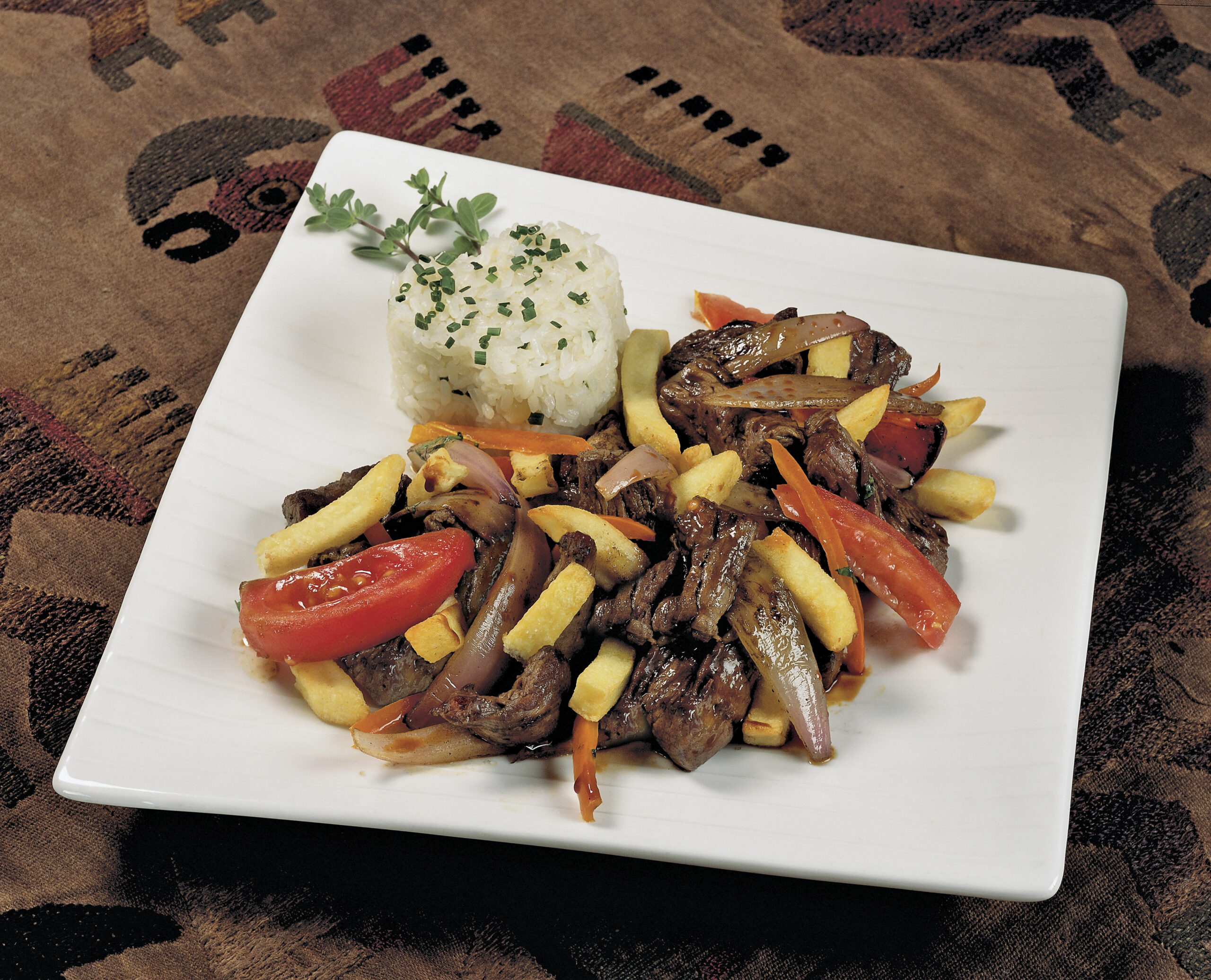 Peruvian food lomo saltado:A salted beef with tomatoes, onion, fried potatoes and rice.