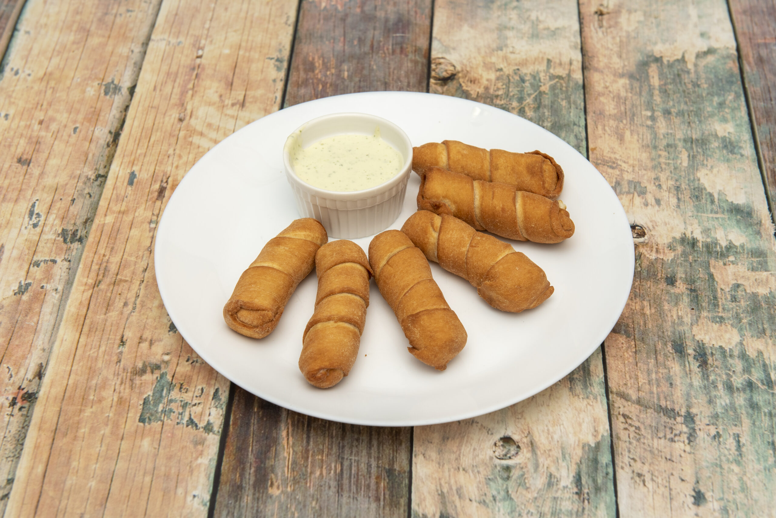 portion of fried Venezuelan tequeños and a small bowl of sauce to dip