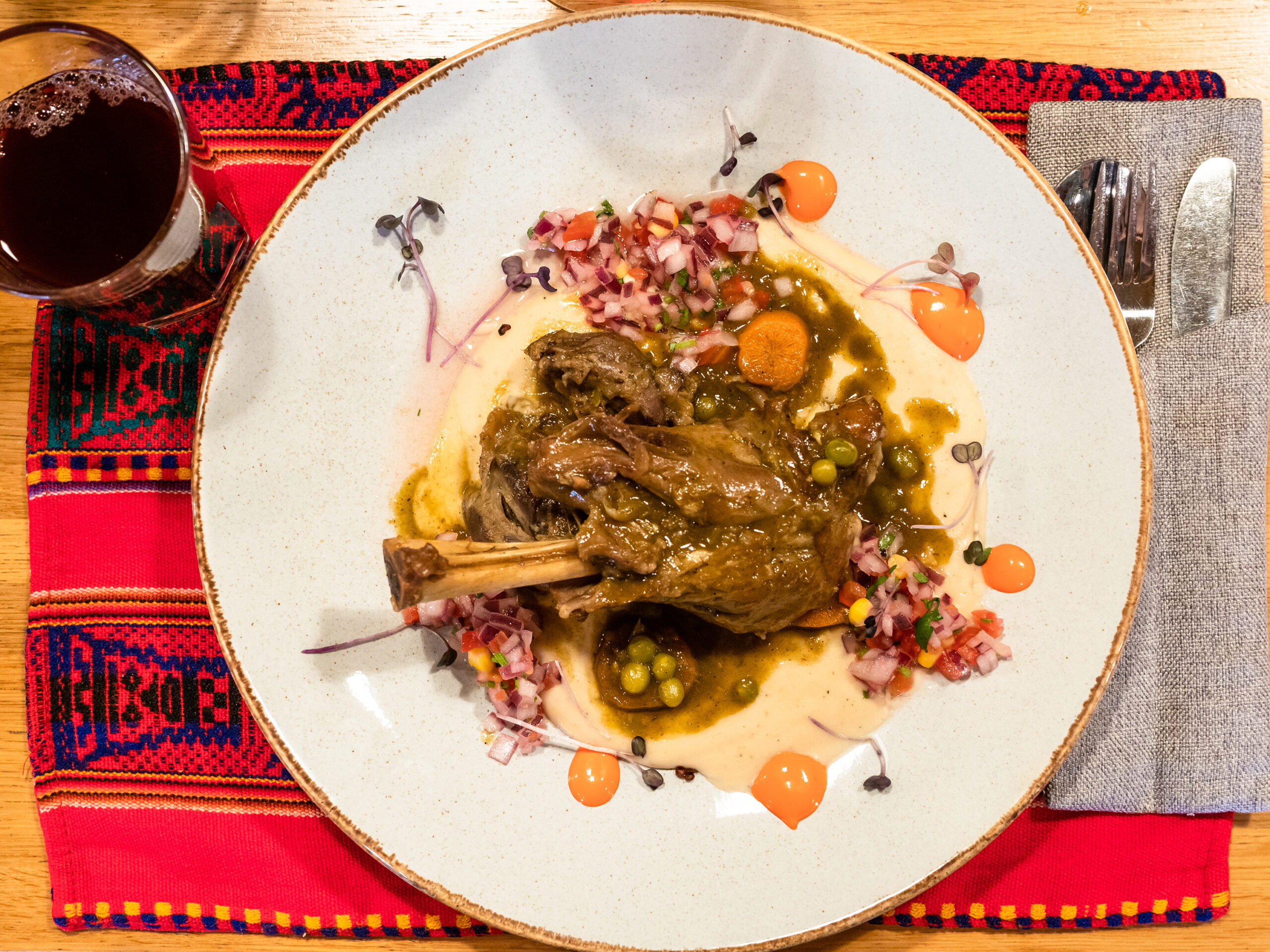 top view of Seco de Cordero - Peruvian dish from stewed lamb shank with mashed beans on plate on table in local restaurant