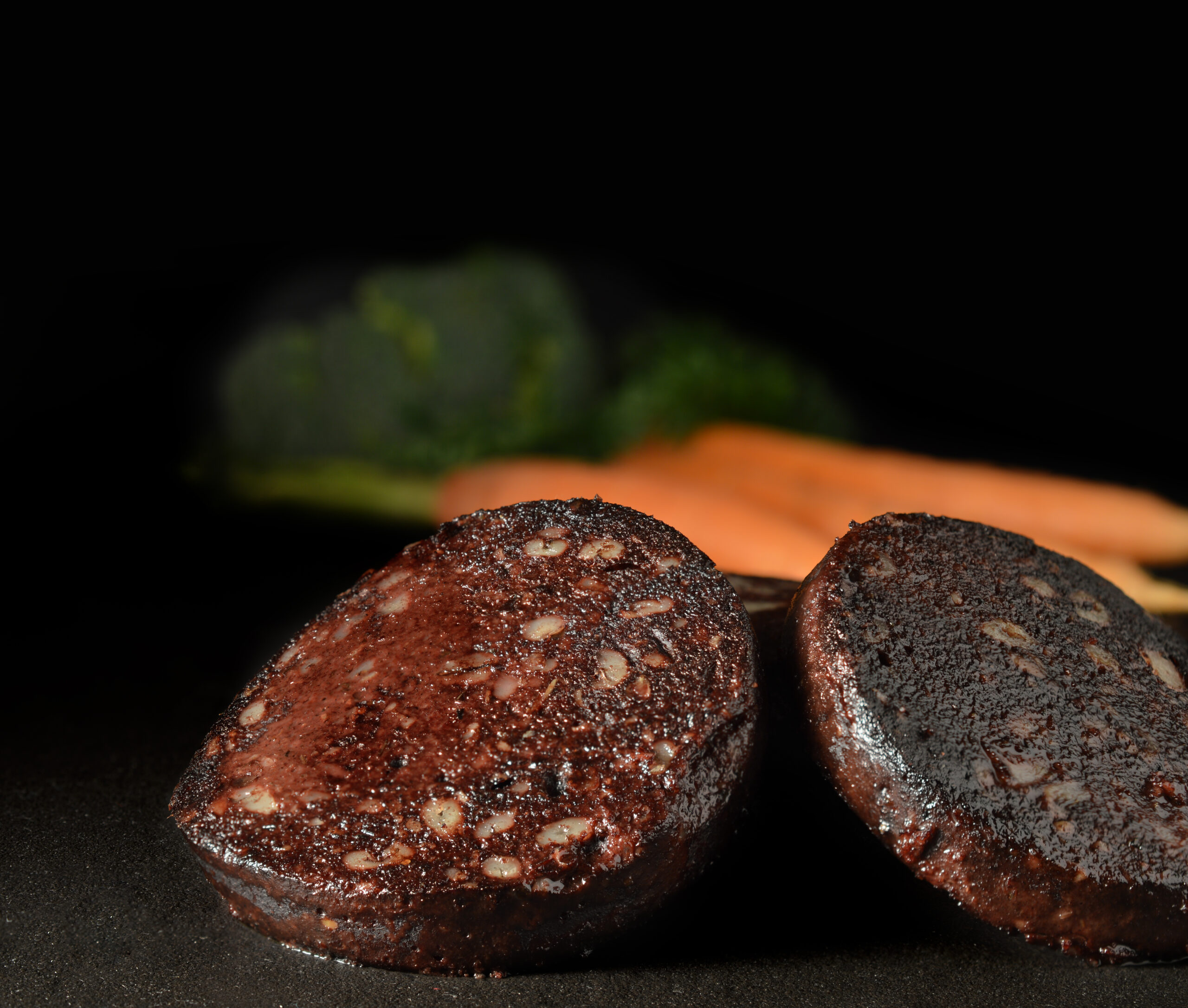 Traditionally English black pudding slices on polished slate. Copy space.