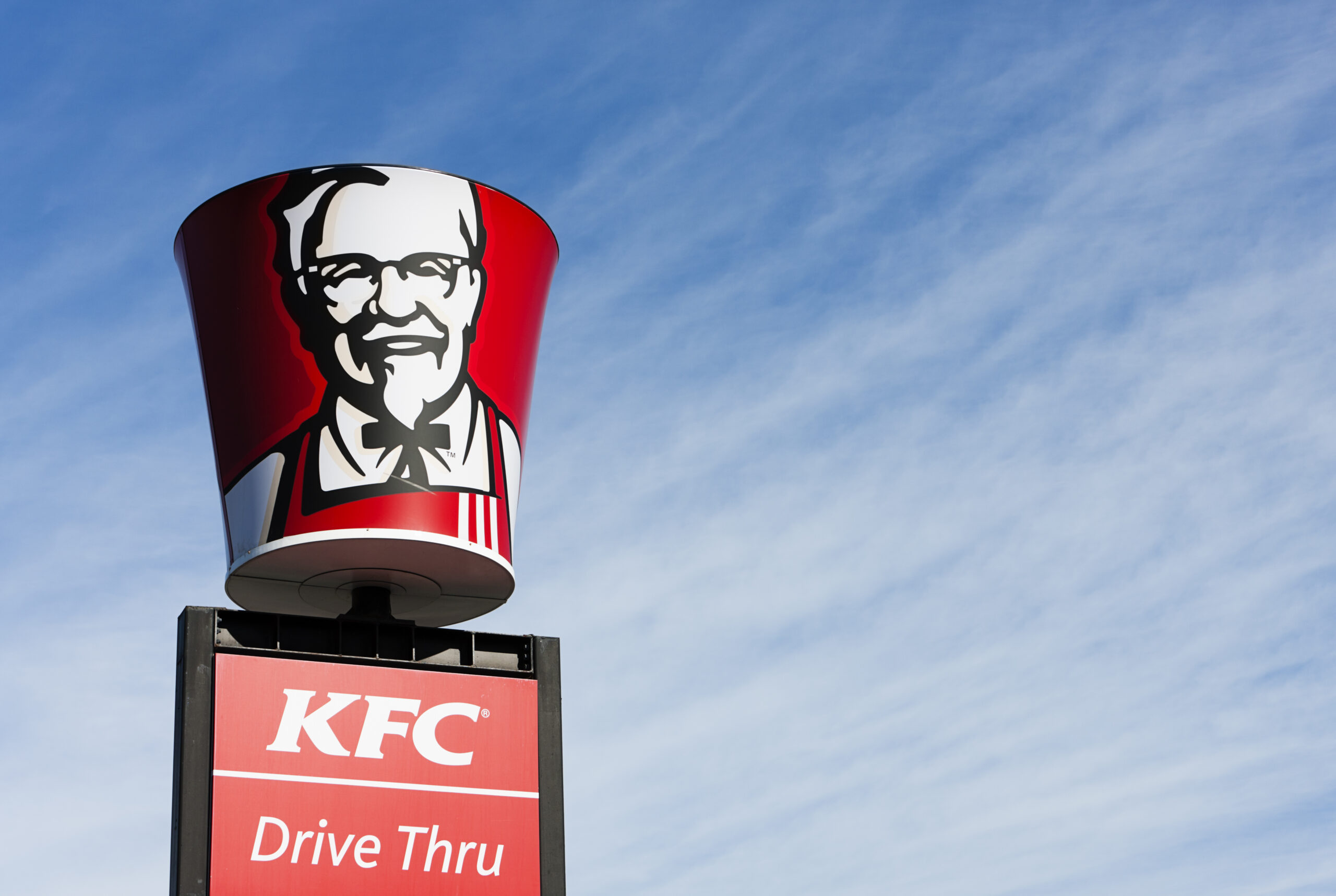 "Cape Town, South Africa - June 21, 2011: A KFC bucket bearing the image of founder Colonel Harland Sanders is placed above a Drive-thru sign at a suburban KFC franchise in Cape Town."