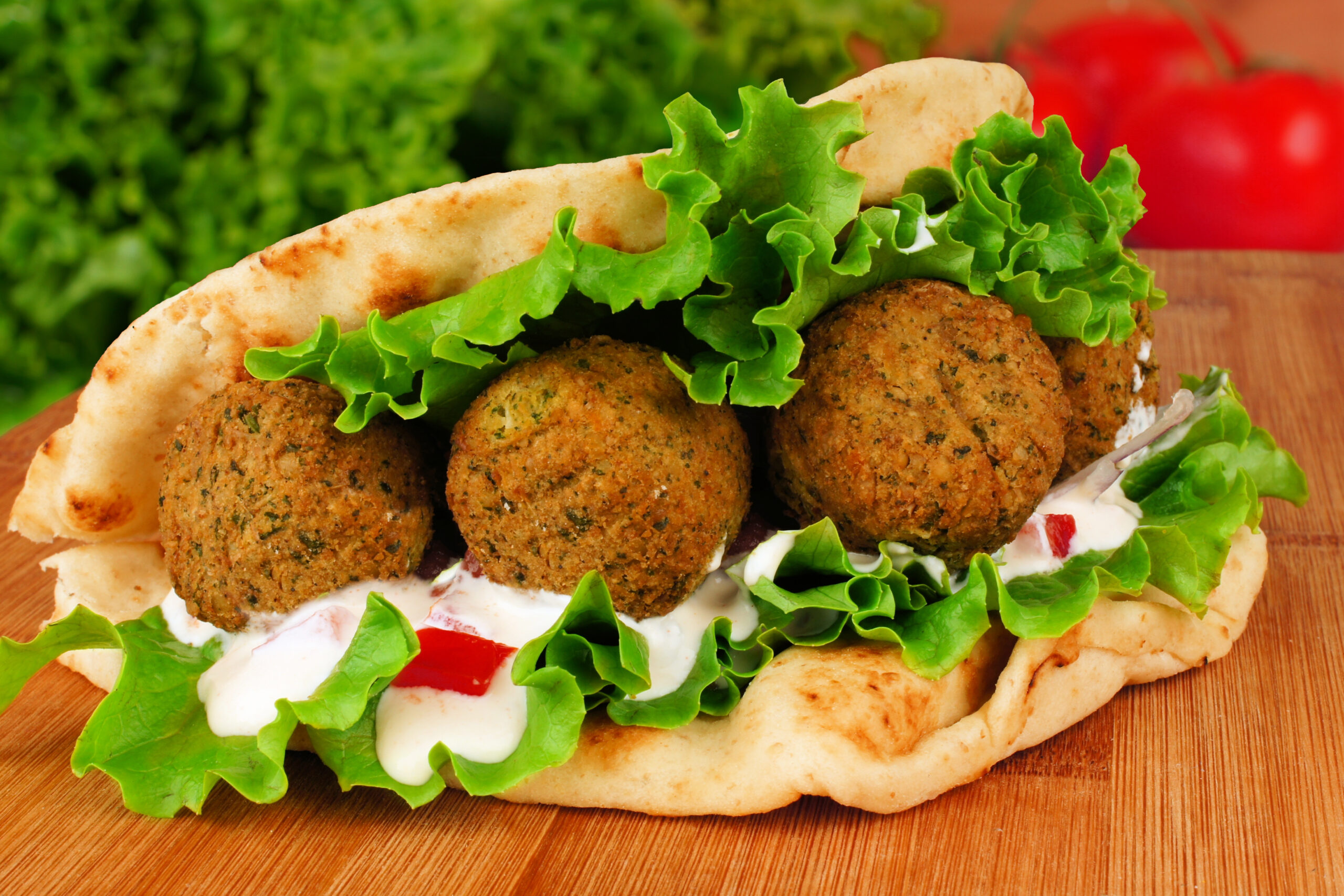 Falafel with vegetables and  tzatziki sauce in pita bread close-up on wooden table