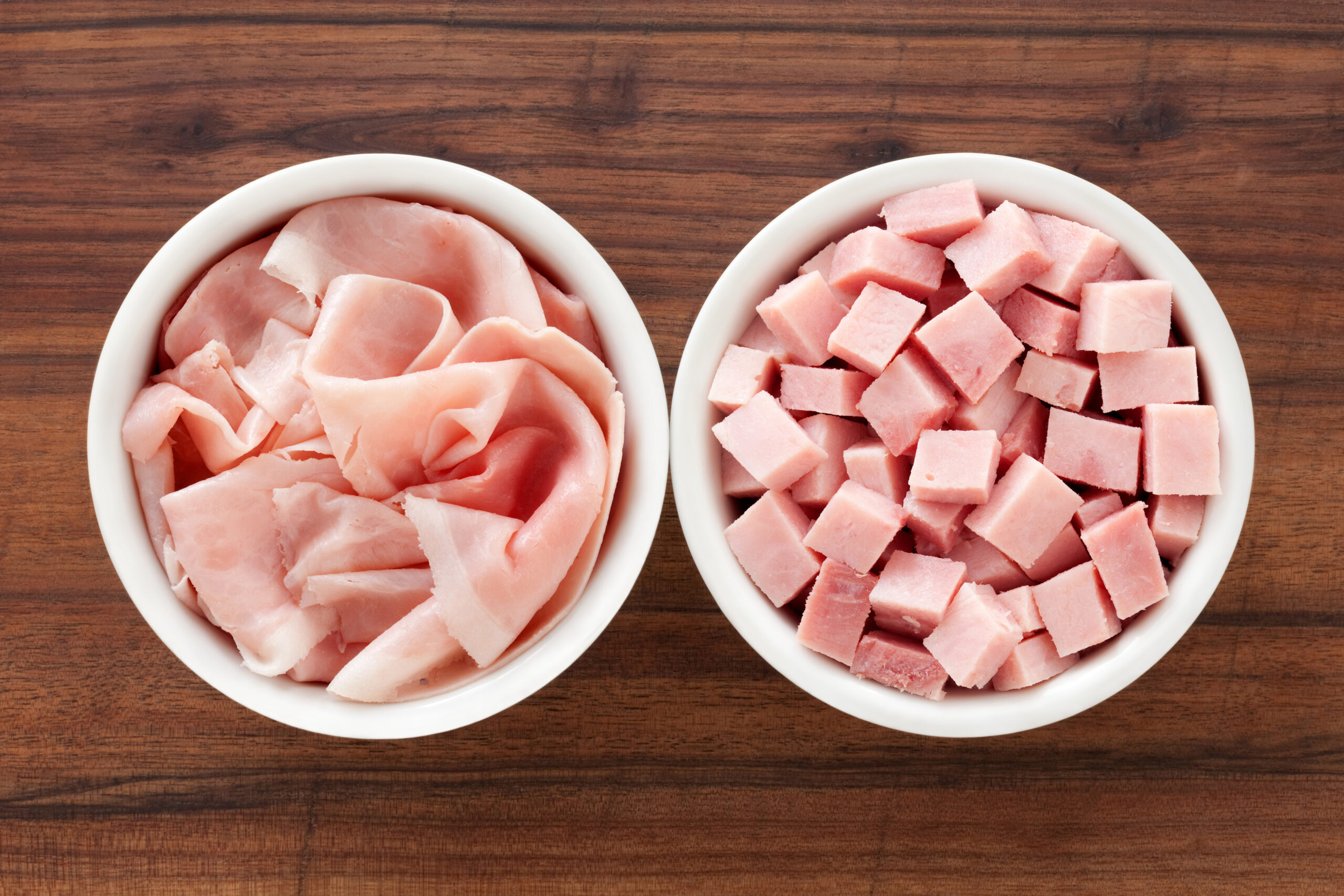 Top view of two bowls side by side with sliced and cubed ham