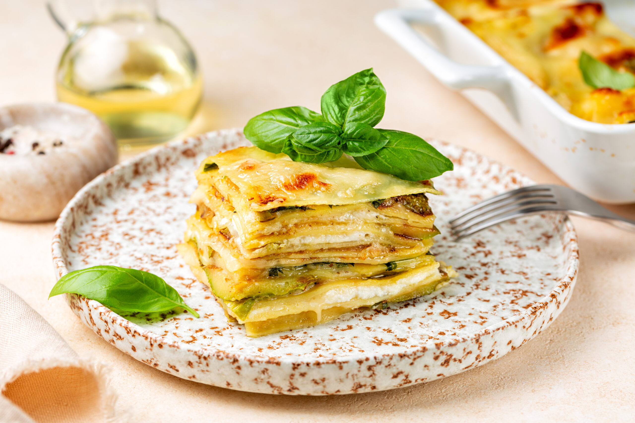 Lasagna with zucchini or courgette, ship cheese, bechamel sauce. Decorated with basil leaves. Vegetarian italian pasta dish.