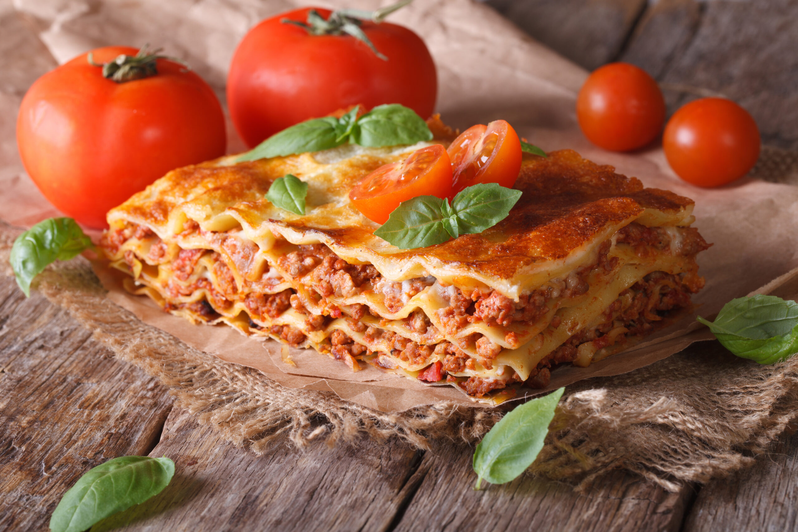 Italian lasagna with basil close-up on paper. horizontal rustic style