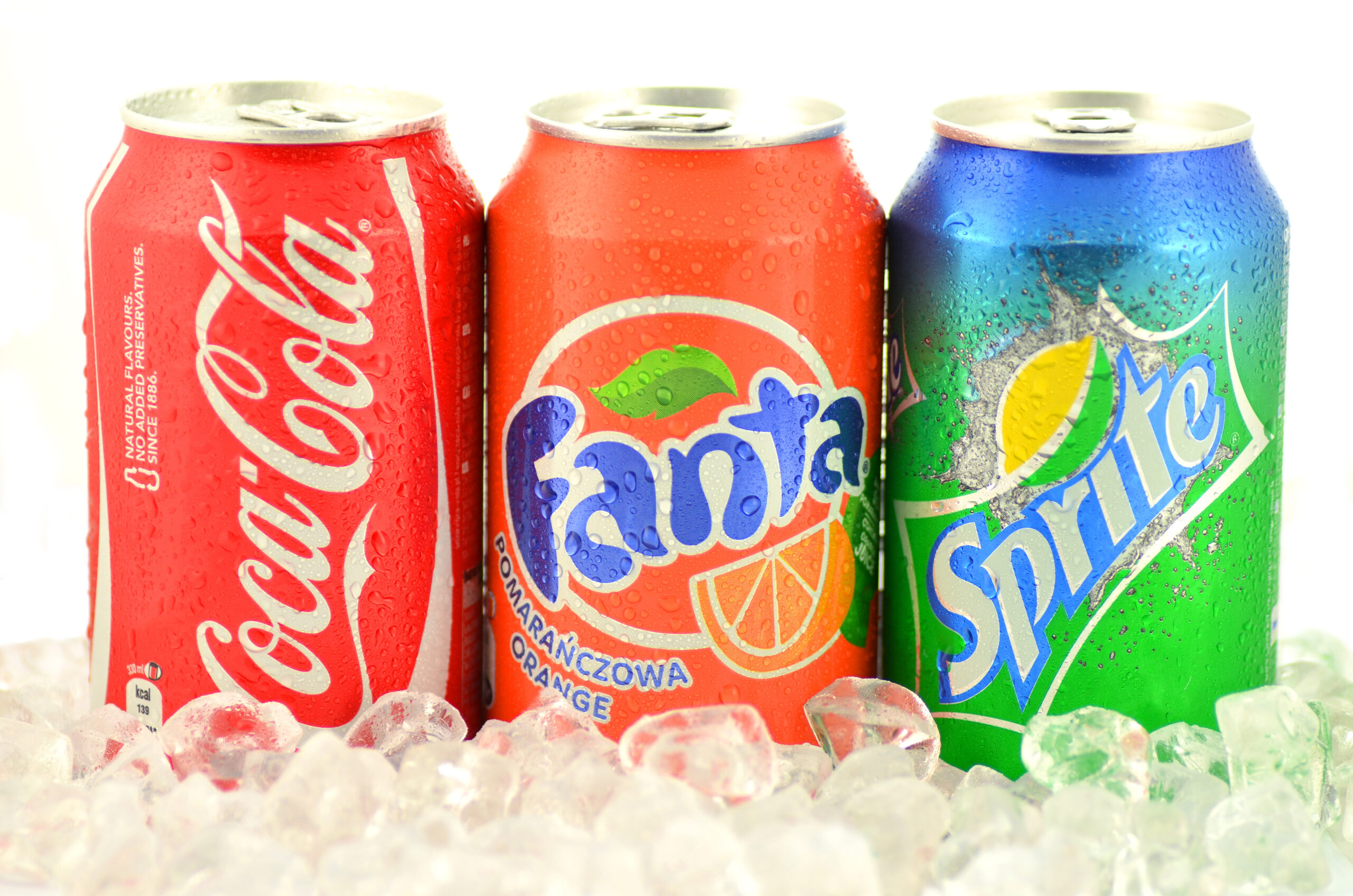 Kwidzyn, Poland - March 15, 2014: Can of Coca-Cola, Fanta and Sprite drinks on ice. They are produced by Coca-Cola Company. Coca-Cola was introduced in 1886, Fanta in 1941 and Sprite in 1961