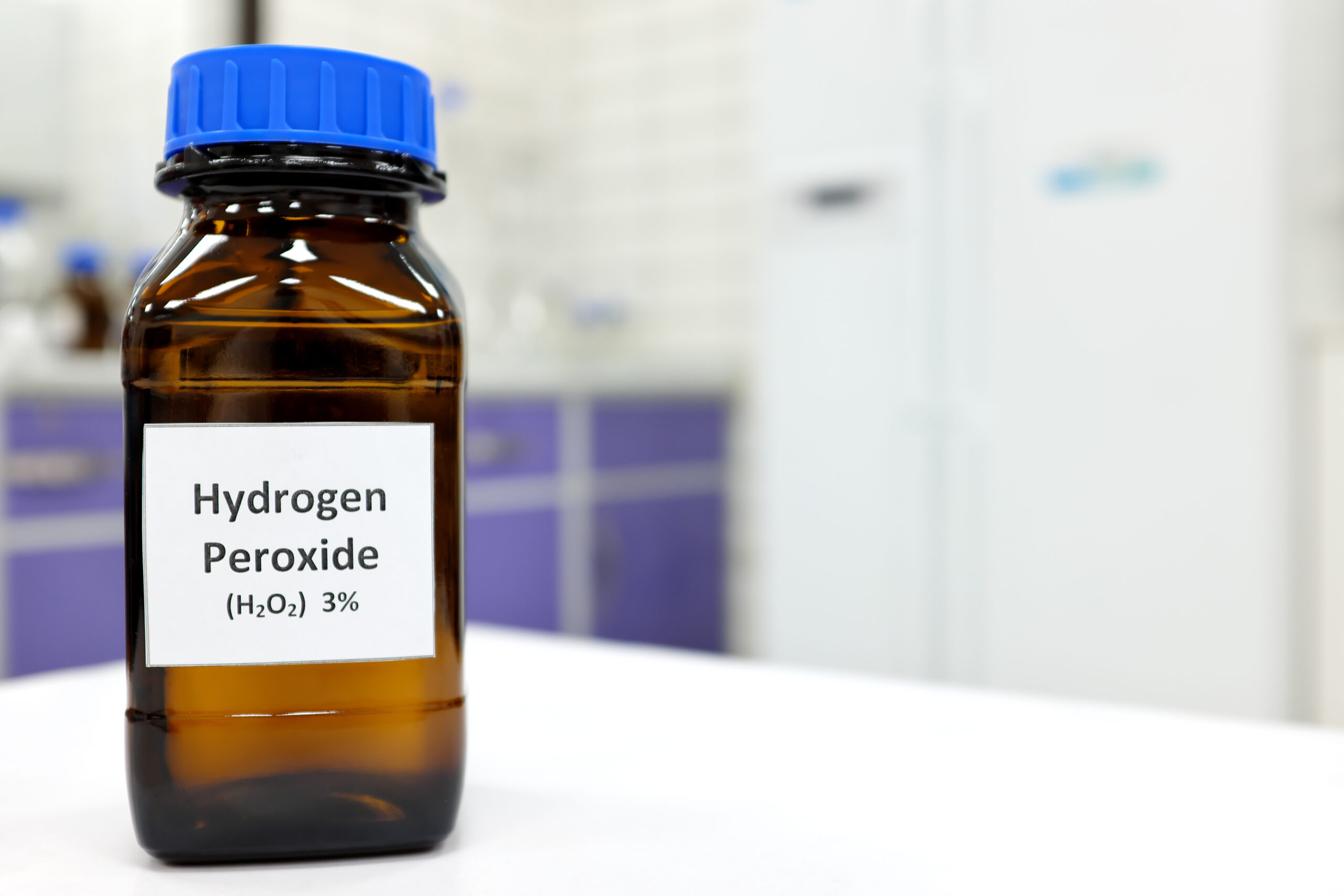 Selective focus of hydrogen peroxide solution in brown amber bottle. Blur laboratory background with copy space.