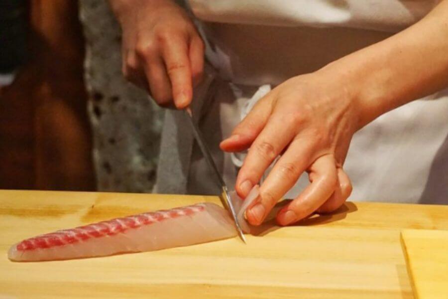 hands of chef cutting fish