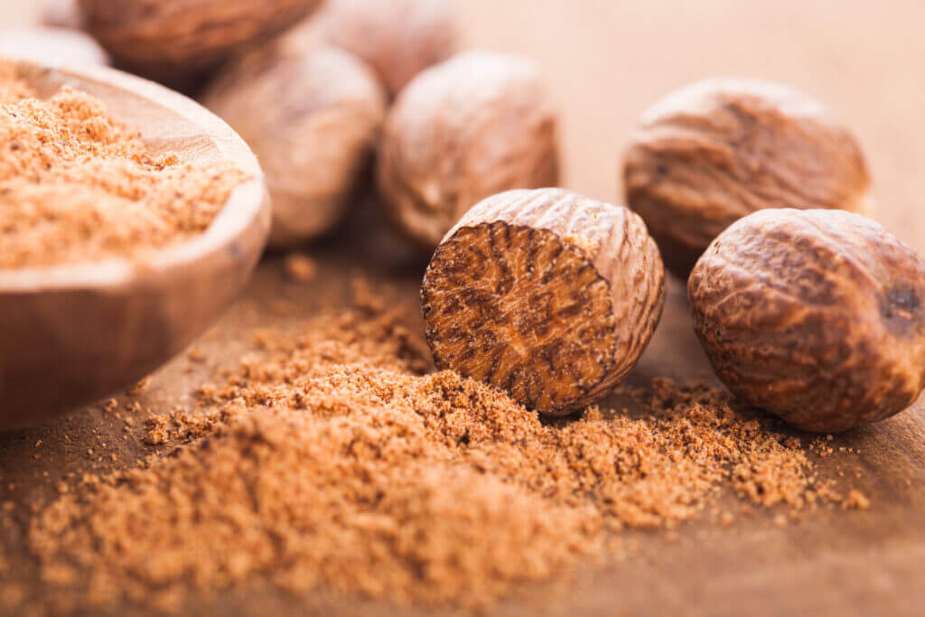 Ground nutmeg spice in the wooden spoon closeup