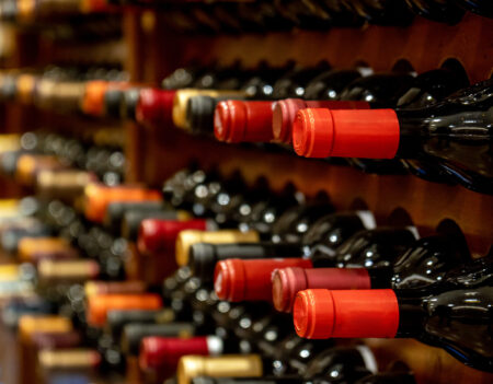 Bottles of black red wine lined up and stacked on wooden wine rack shelves