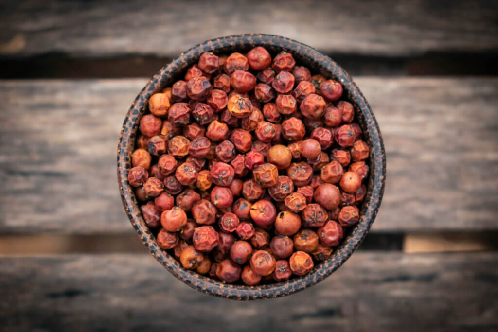 organic kampot dried red pepper corns in cambodia in traditonal asian wood bowl