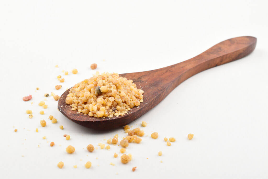 Asafoetida in spoon on white background, heeng or hing in wooden spoon indian spice