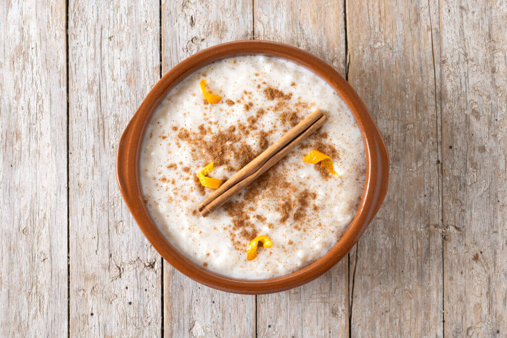 Arroz con leche with cinnamon in clay bowl on wooden table