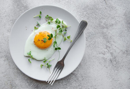 Fried eggs on a white plate on concrete background