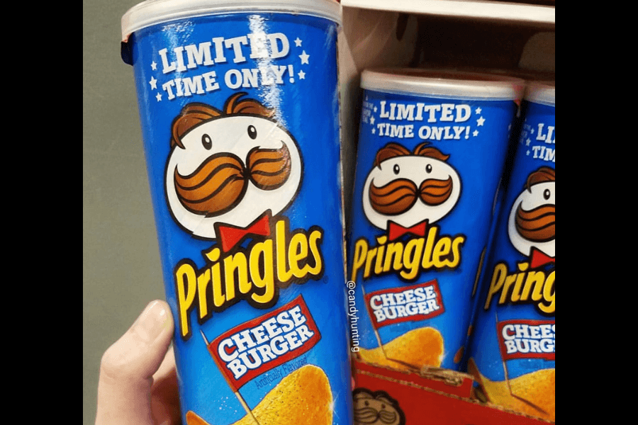 A can of Pringles in the "Cheeseburger" flavor with a bright blue design, labeled "Limited Time Only!" in bold white text surrounded by stars. The can features the Pringles mascot and a depiction of a cheeseburger-flavored chip with a small red flag reading "Cheese Burger." Multiple cans are displayed in the background as part of a store display.