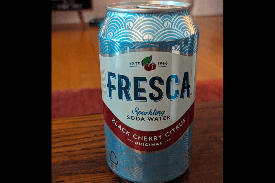 This image shows a can of Fresca sparkling soda water in the Black Cherry Citrus flavor. The design features a blue and white wave pattern with bold navy lettering, accented by a small cherry illustration and a red band at the bottom highlighting the flavor.