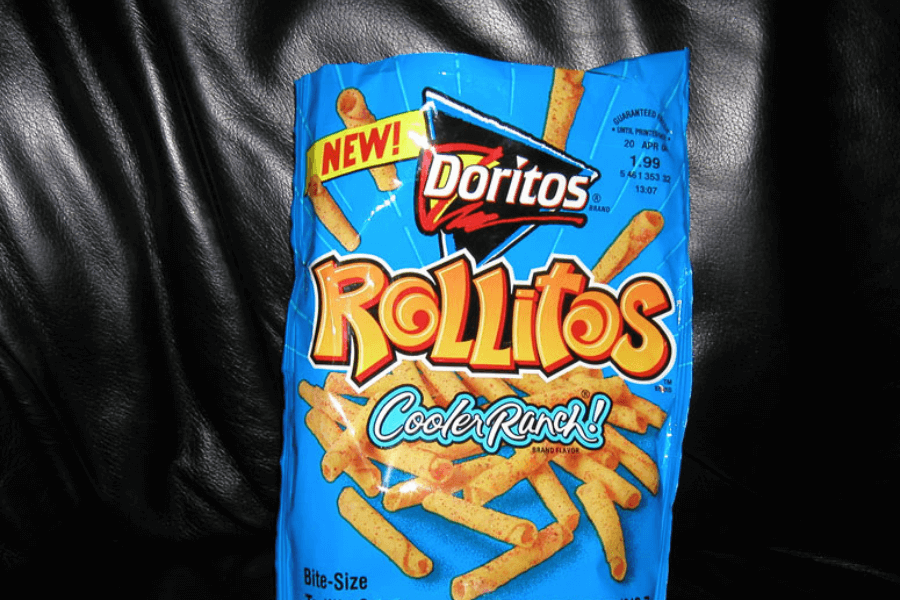 A bag of Doritos Rollitos in the "Cooler Ranch" flavor, featuring a bright blue design. The packaging highlights the rolled, bite-sized chips with seasoning specks and a "NEW!" label at the top. The bag is displayed against a black leather background.