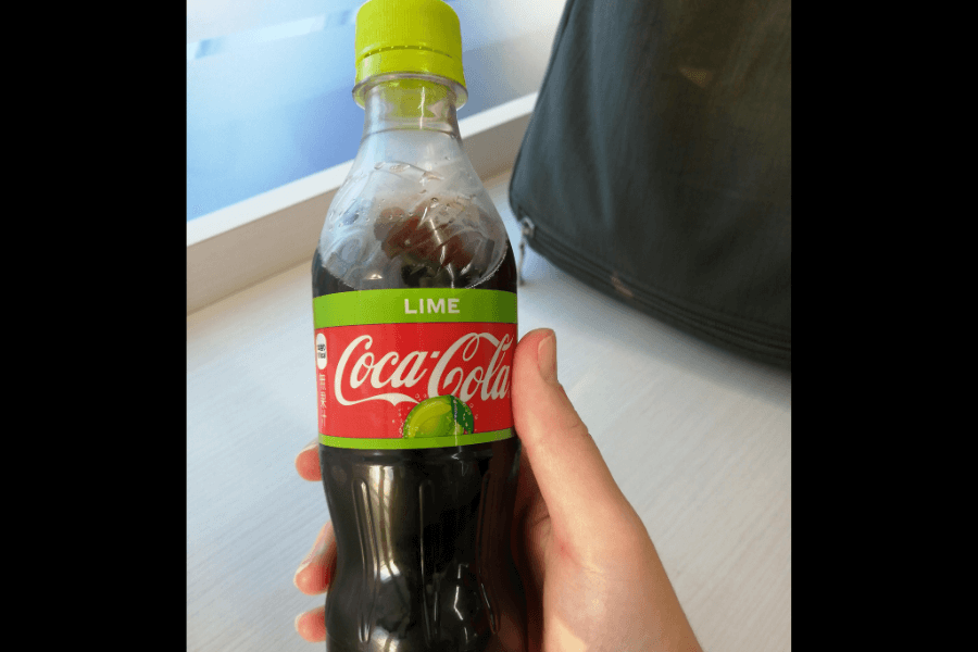 This image shows a bottle of Coca-Cola Lime, featuring a green cap and a matching label with a lime graphic beneath the classic Coca-Cola branding. The design highlights its lime-flavored twist, giving a refreshing and zesty appeal.