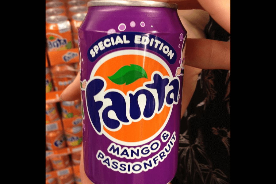 This image shows a special edition can of Fanta Mango & Passionfruit, featuring a vibrant purple background with the classic Fanta logo and orange accents. The design highlights its tropical flavor, making it stand out on the shelf in the background.