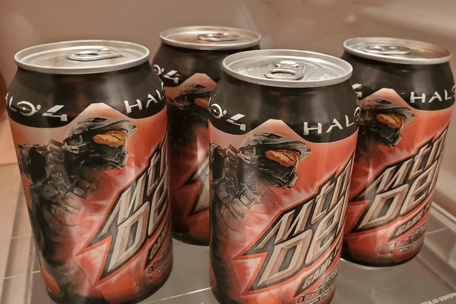 This image features four cans of Mountain Dew Game Fuel, themed around "Halo 4" with bold black and orange graphics. The cans display an image of the Halo protagonist, Master Chief, tying the branding to the popular video game franchise for an energetic and gamer-focused appeal.