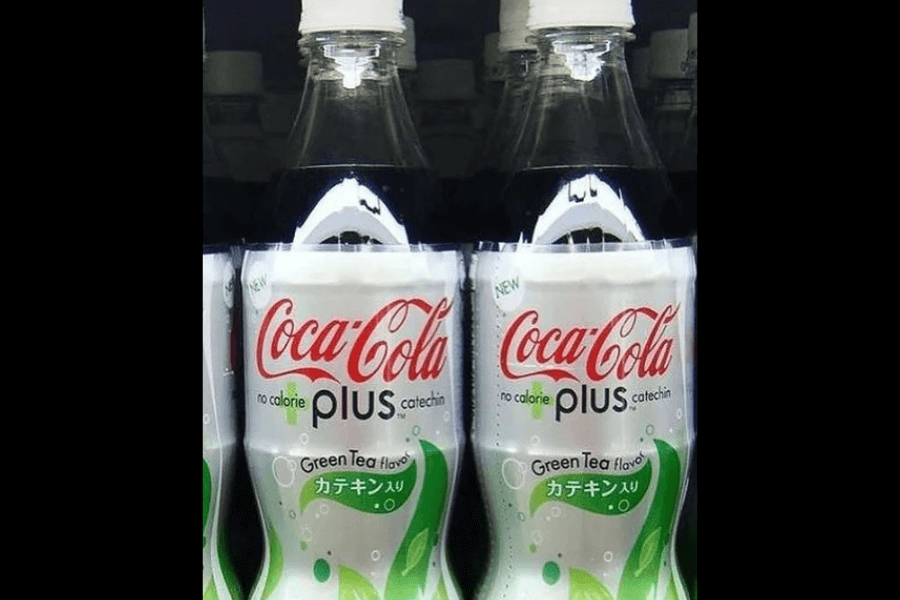 This image features bottles of Coca-Cola Plus, a no-calorie beverage with green tea flavor and catechin, as indicated on the label. The design is sleek and modern, incorporating white and green elements to emphasize its health-oriented and refreshing qualities.