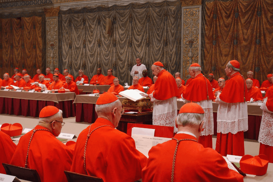 Cardinals dressed in red vestments participate in a papal conclave within the ornate setting of the Sistine Chapel, seated around tables and casting ballots, with ceremonial officials overseeing the process near the altar.