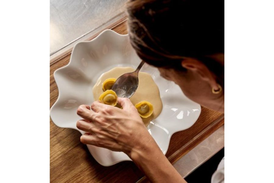 Mujer acomodando pequeños y delicados ravioles en un plato