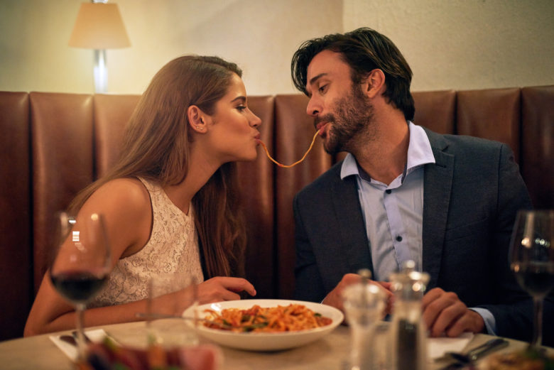 A young couple sharing spaghetti on a date