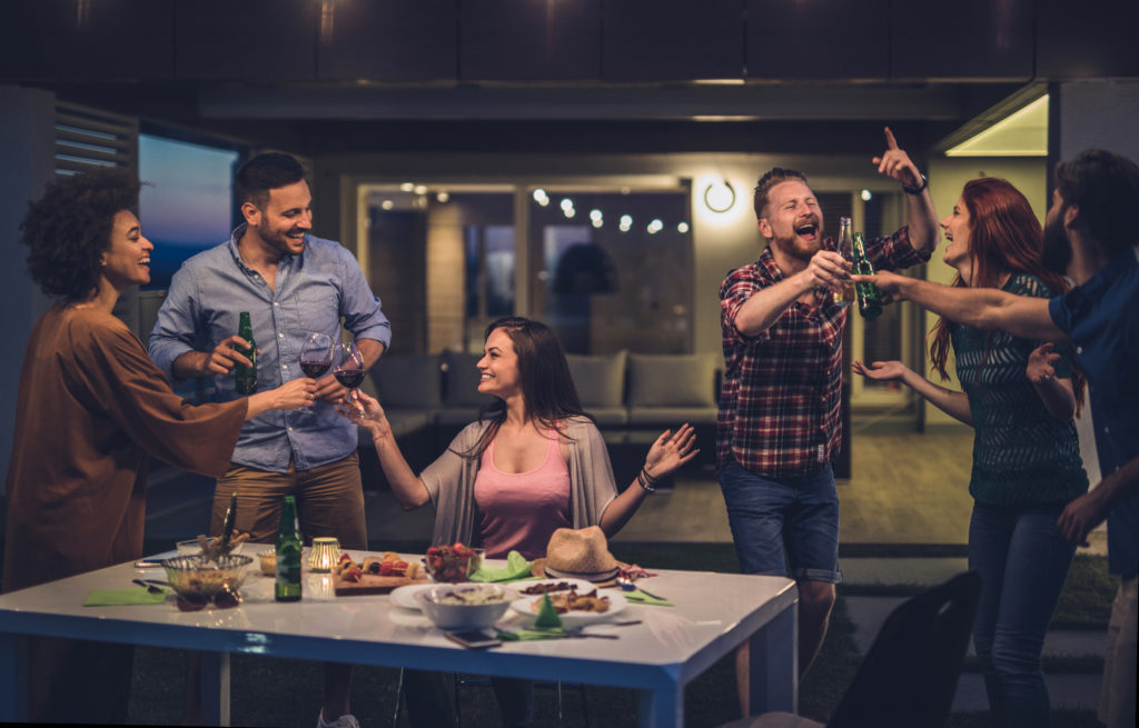 Large group of friends having fun on night party while toasting with drinks.