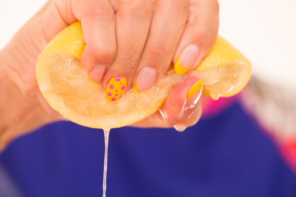 Woman With Polished Fingernails Squeezing and Orange