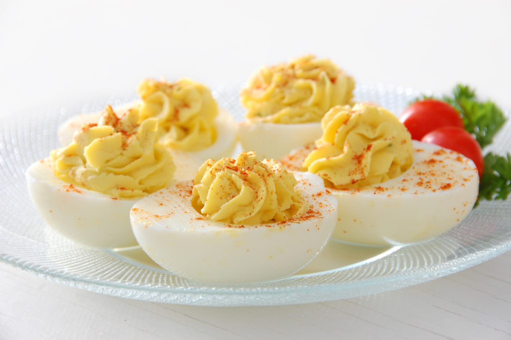 A plate of deviled eggs, sprinkled with paprika.