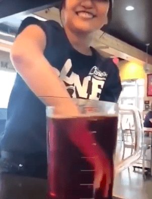 fast food worker stirs iced tea with her arm