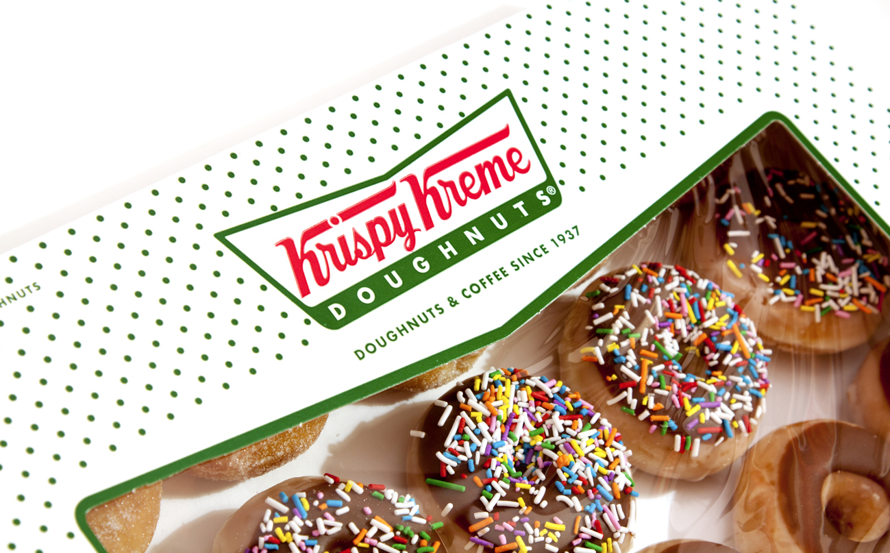 Krispy Kreme doughnuts with chocolate icing and colorful sprinkles in branded box.