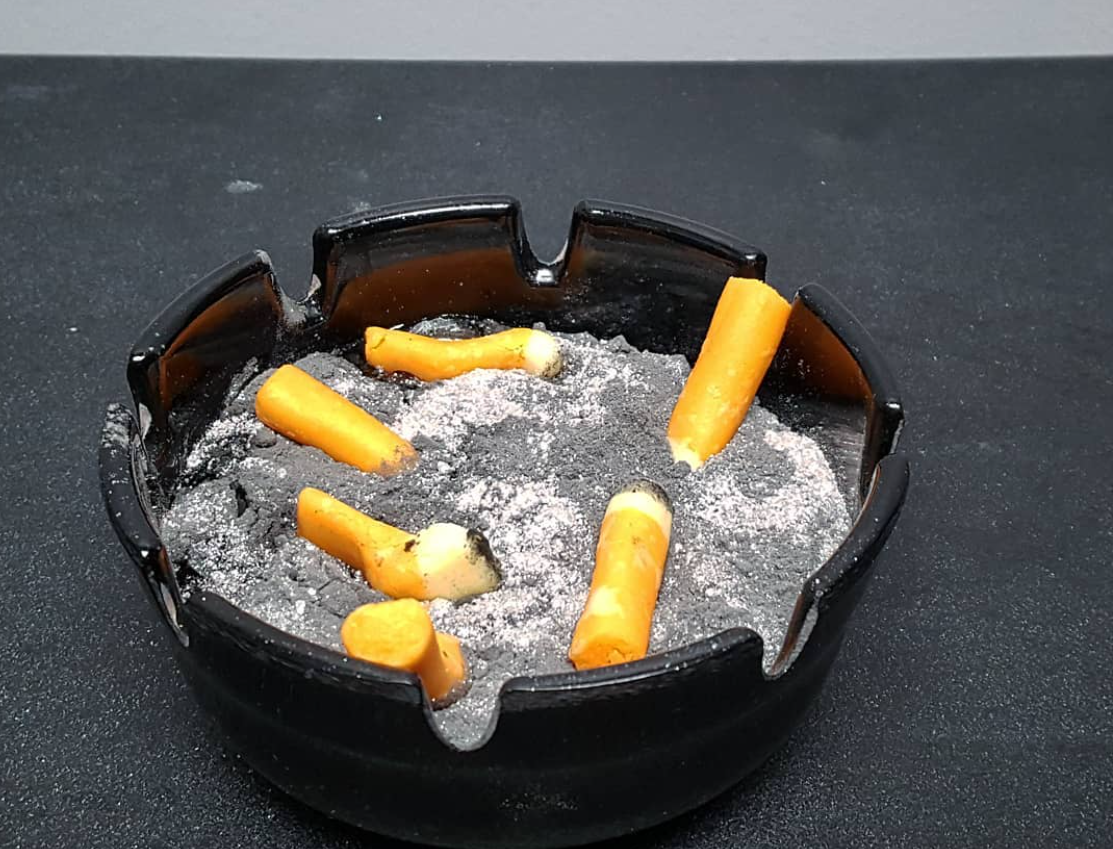 Black ashtray filled with ash and cigarette butts, optical illusion made out of food, from chefbenchurchill instagram