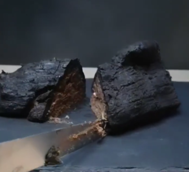 knife cutting into a burnt log that is actually a cake, by chefbenchurchill on instagram